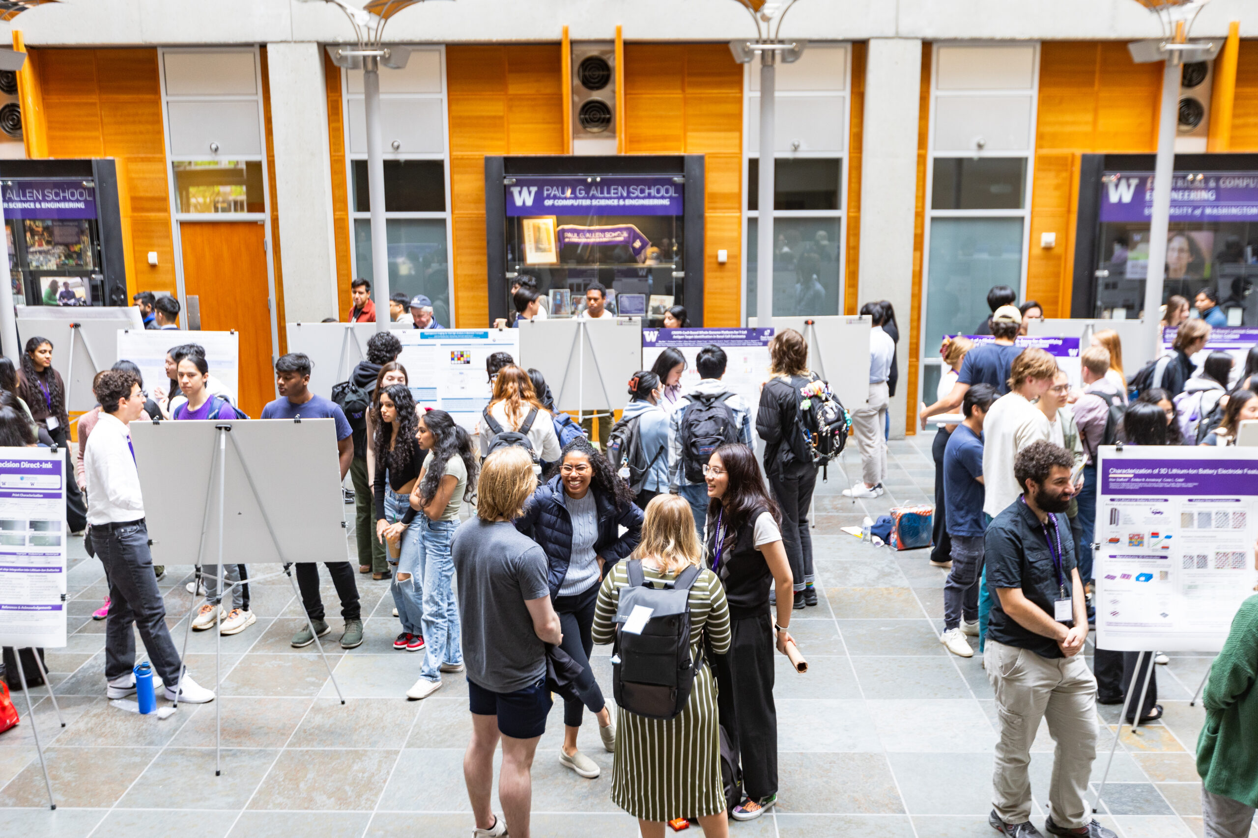 a view from above of the hall with undergrad researchers standing beside their exhibits talking to visitors