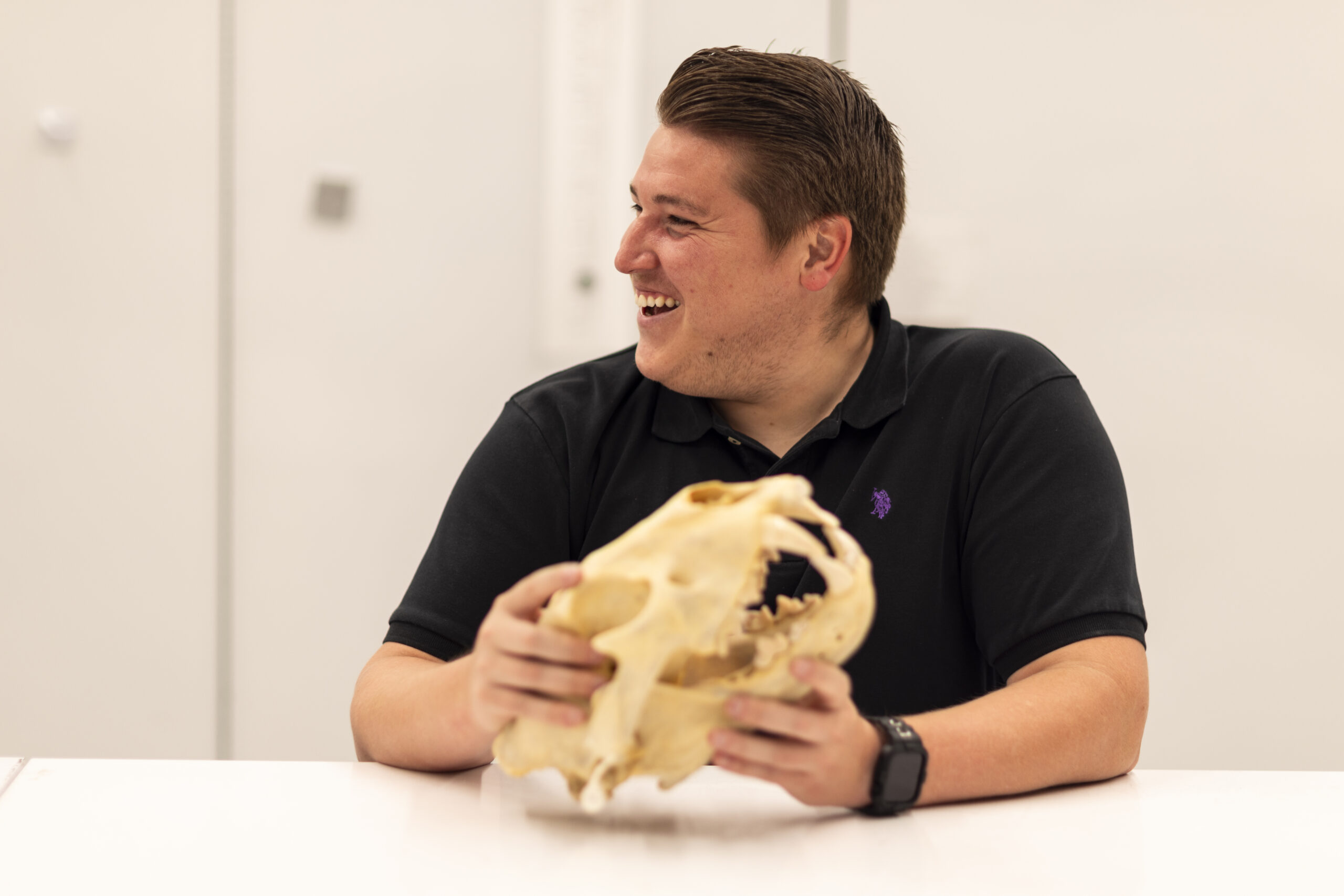 laughing postdoctoral researcher holding a lion skull