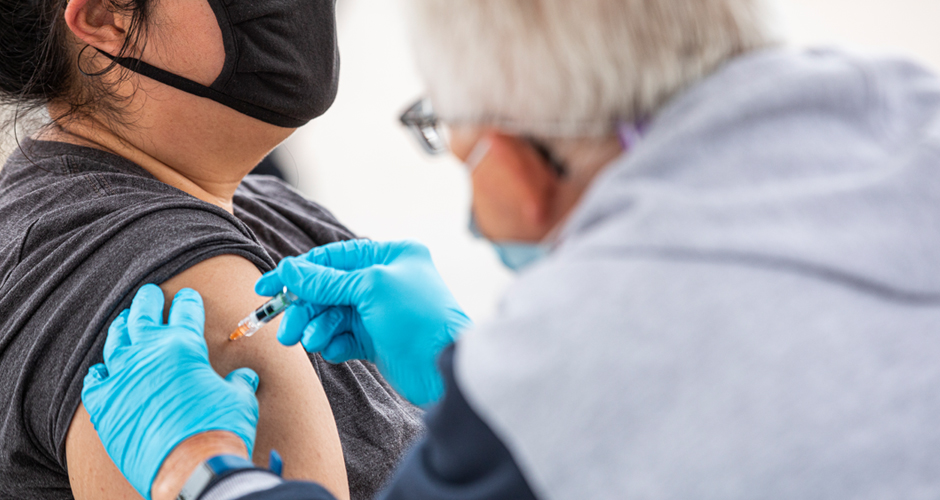 Medical doctor administers a shot in a patients upper arm