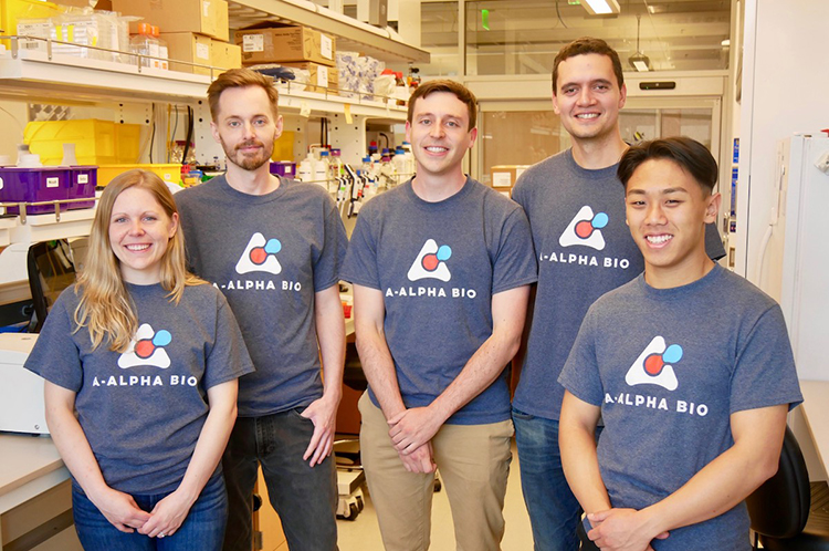 A group of researchers wearing the same shirt with their brand logo stand in a lab at Comotion