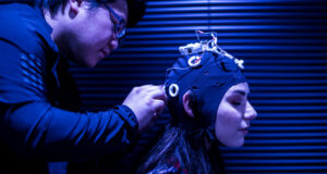 A scientist fits a cap with electrode sensors to a patients head